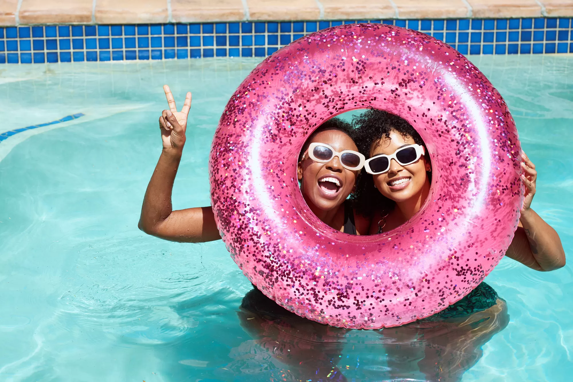 Two women in a pool with a pink floatie