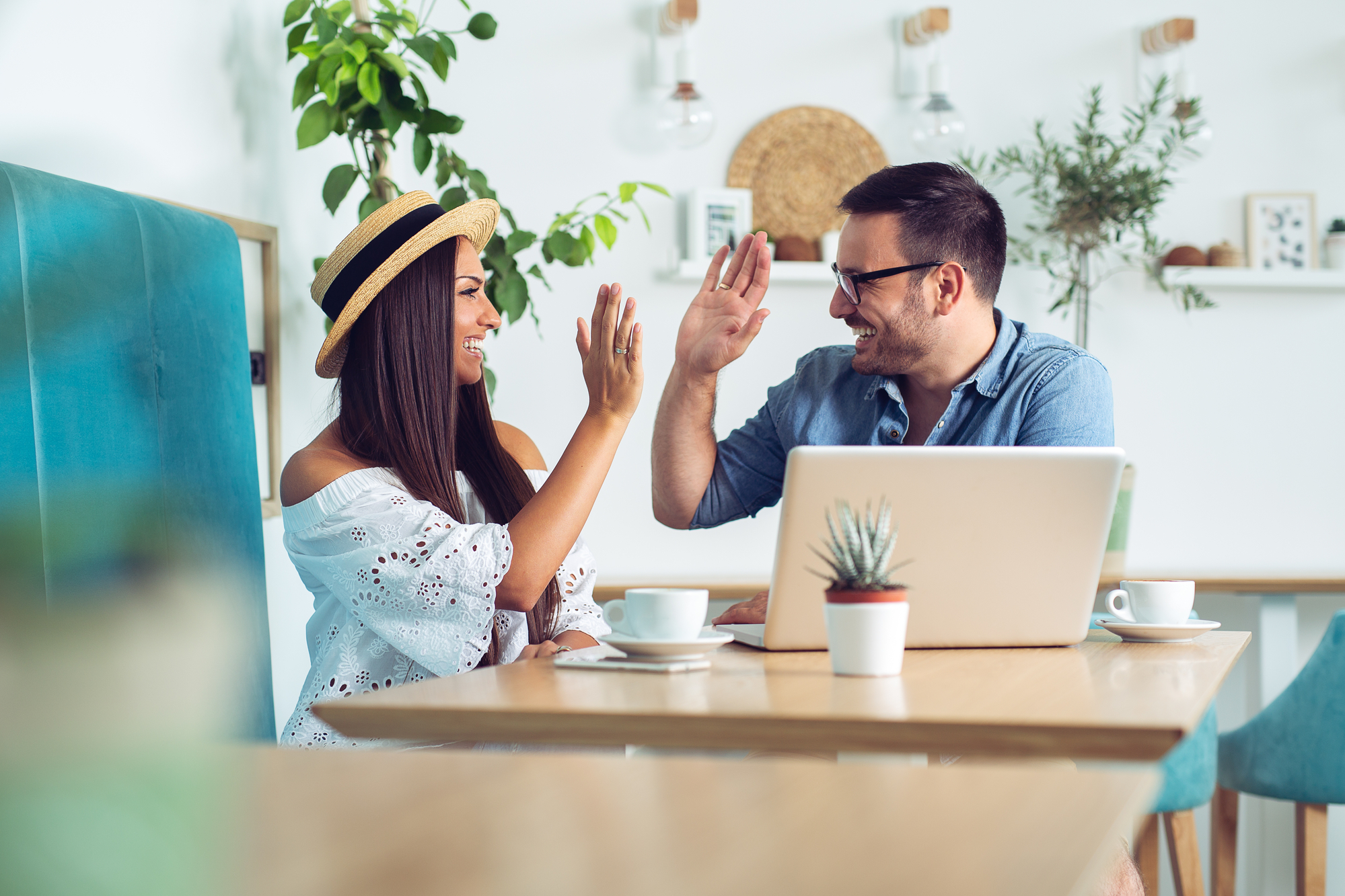 young couple sitting at computer high fiving