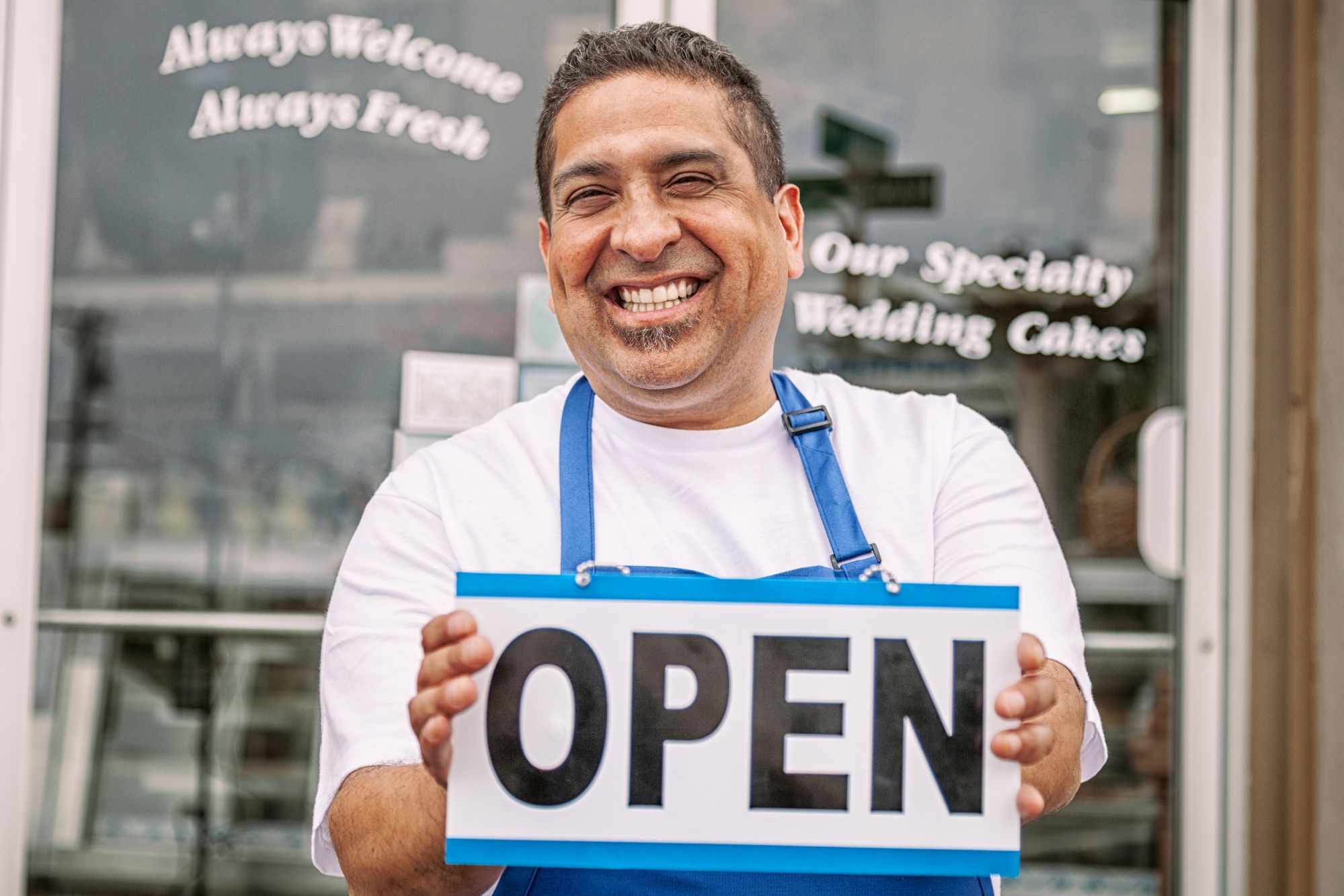 Small business owner holding "open" sign