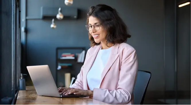 woman in pink suit sitting at laptop