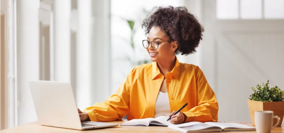 woman in yellow shirt smiling at laptop