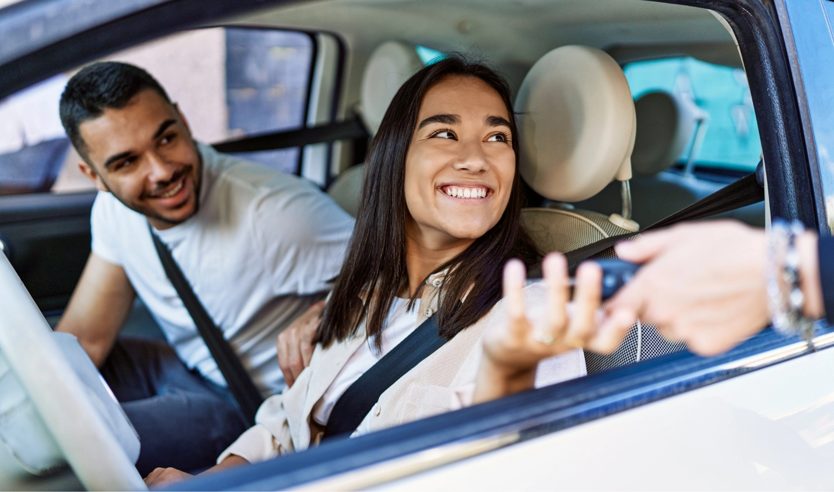 two people in a car being handed the keys