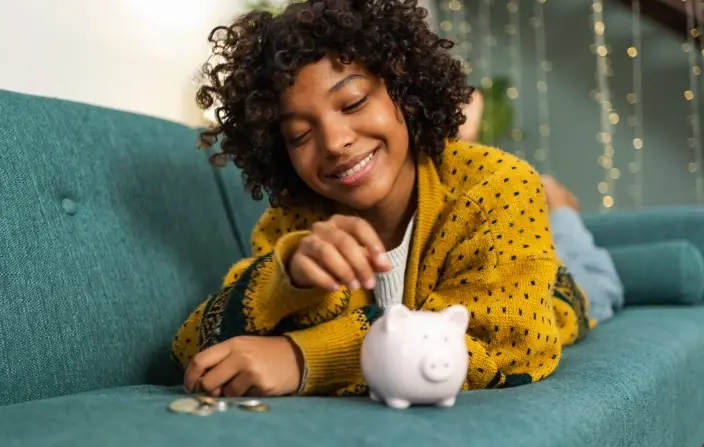 young woman putting money into piggy bank